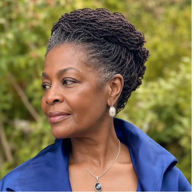 Black woman over 50 with a crown-twist Sisterlocks updo