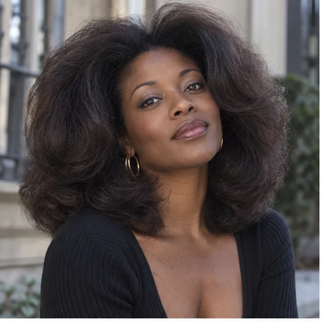 Black woman with stretched coily hair in a full rounded 90s blowout