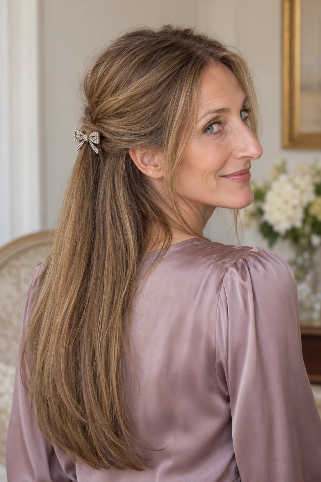 A small crystal bow barrette finishes a gathered half-up section above straight dark blonde lengths.